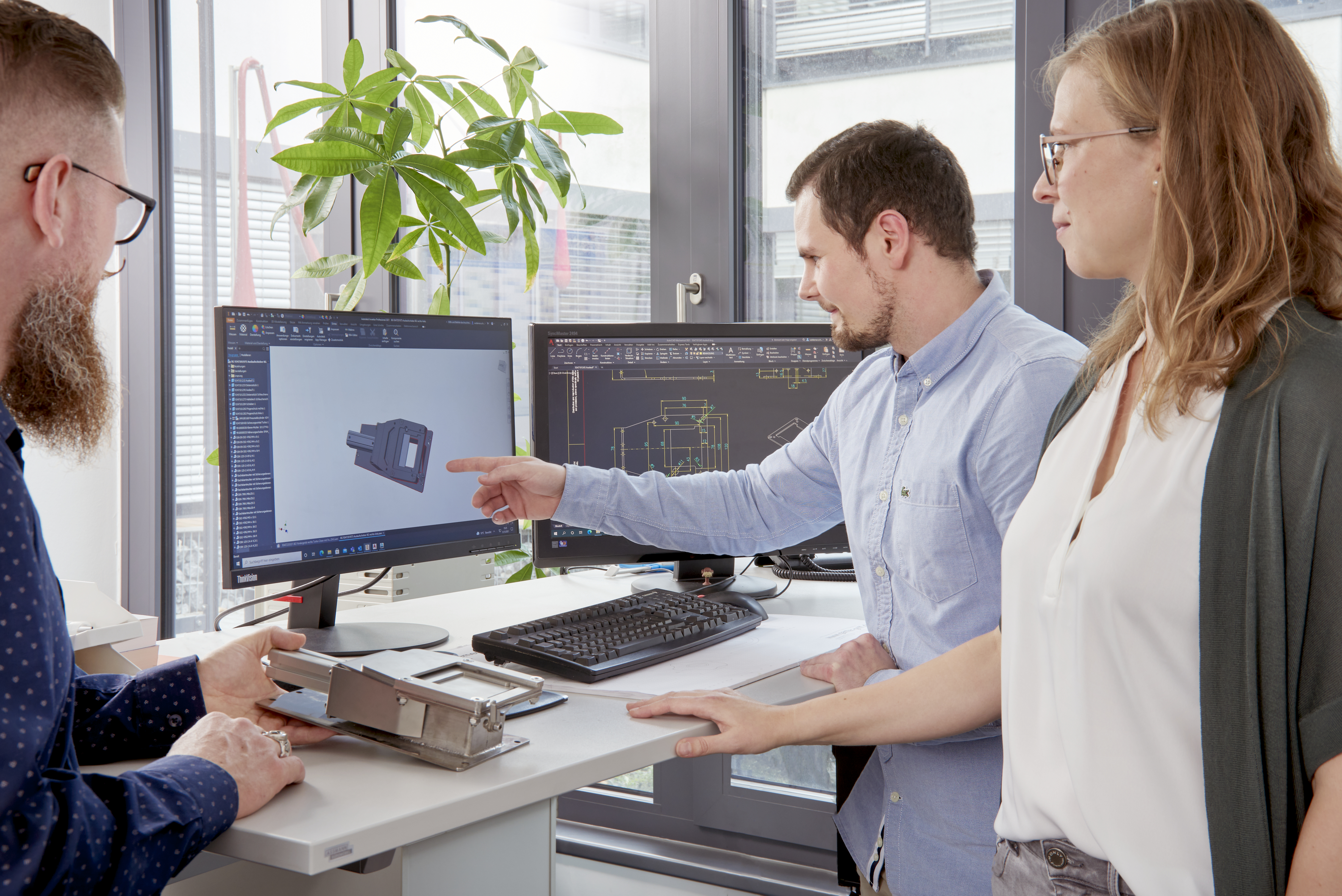 Employees discuss a design on the CAD system.