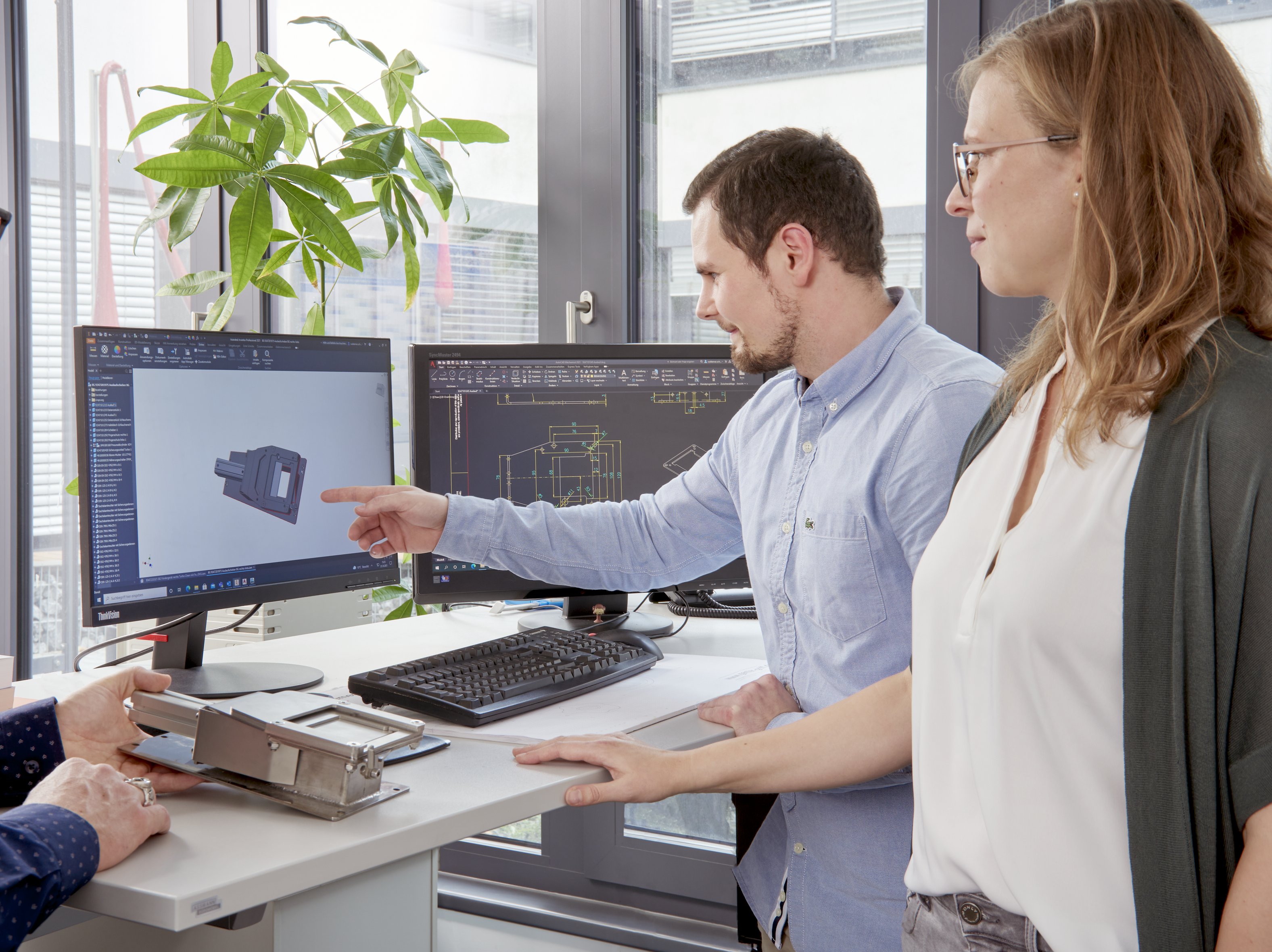 Mitarbeitende besprechen eine Konstruktion an der CAD Anlage.